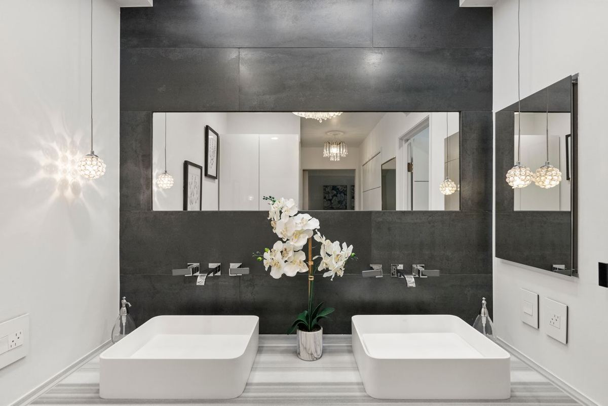 Primary bathroom with stone wall, twin vessel sinks and crystal pendants, from one of Tomas's listings