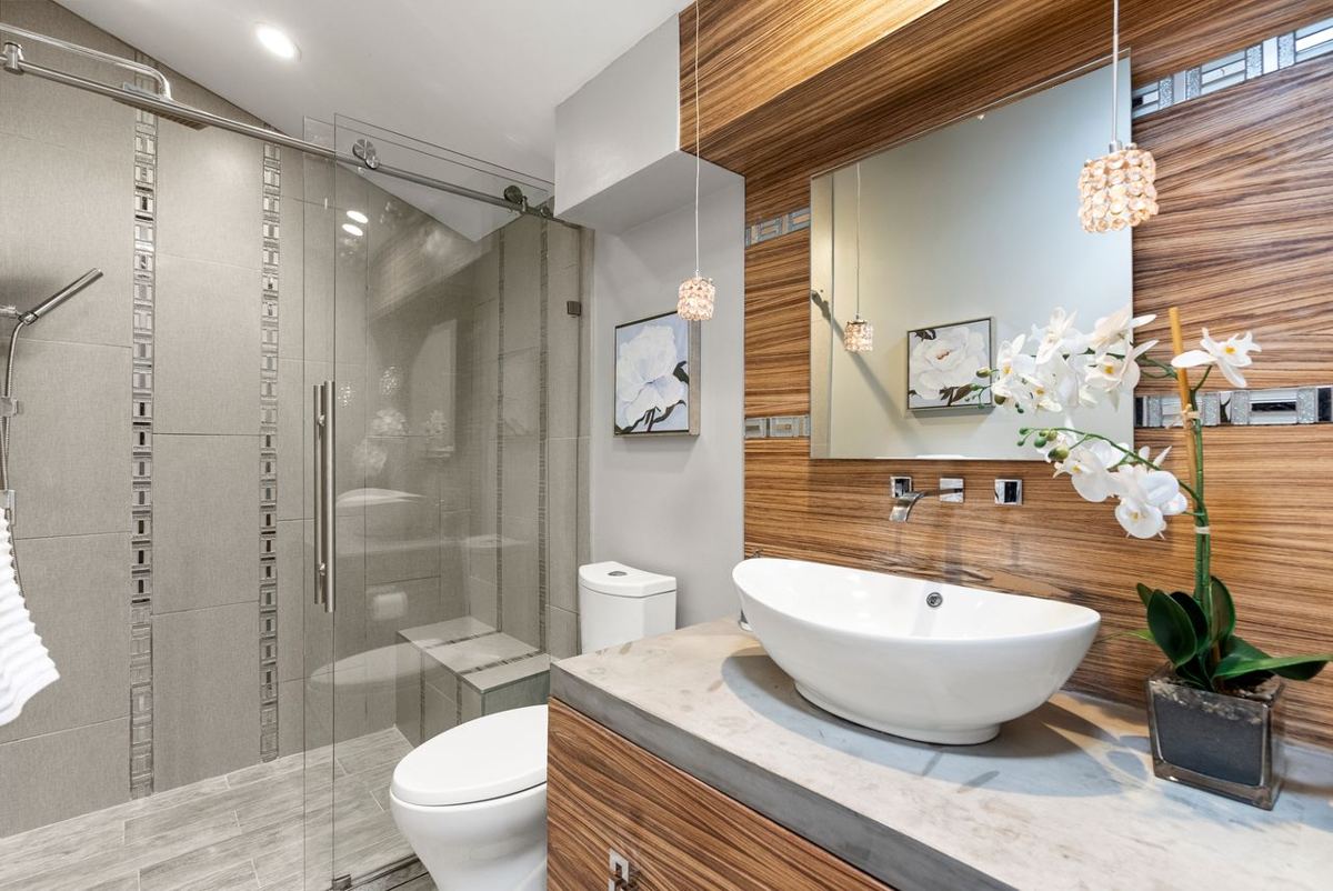 Bathroom with wood-grain wall, vessel sink and glass shower
