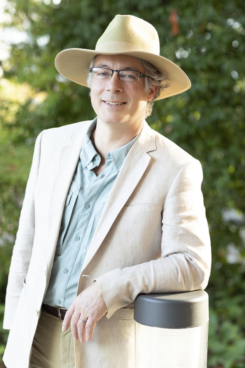 Tomas Kandl in a linen jacket and hat, smiling in a garden